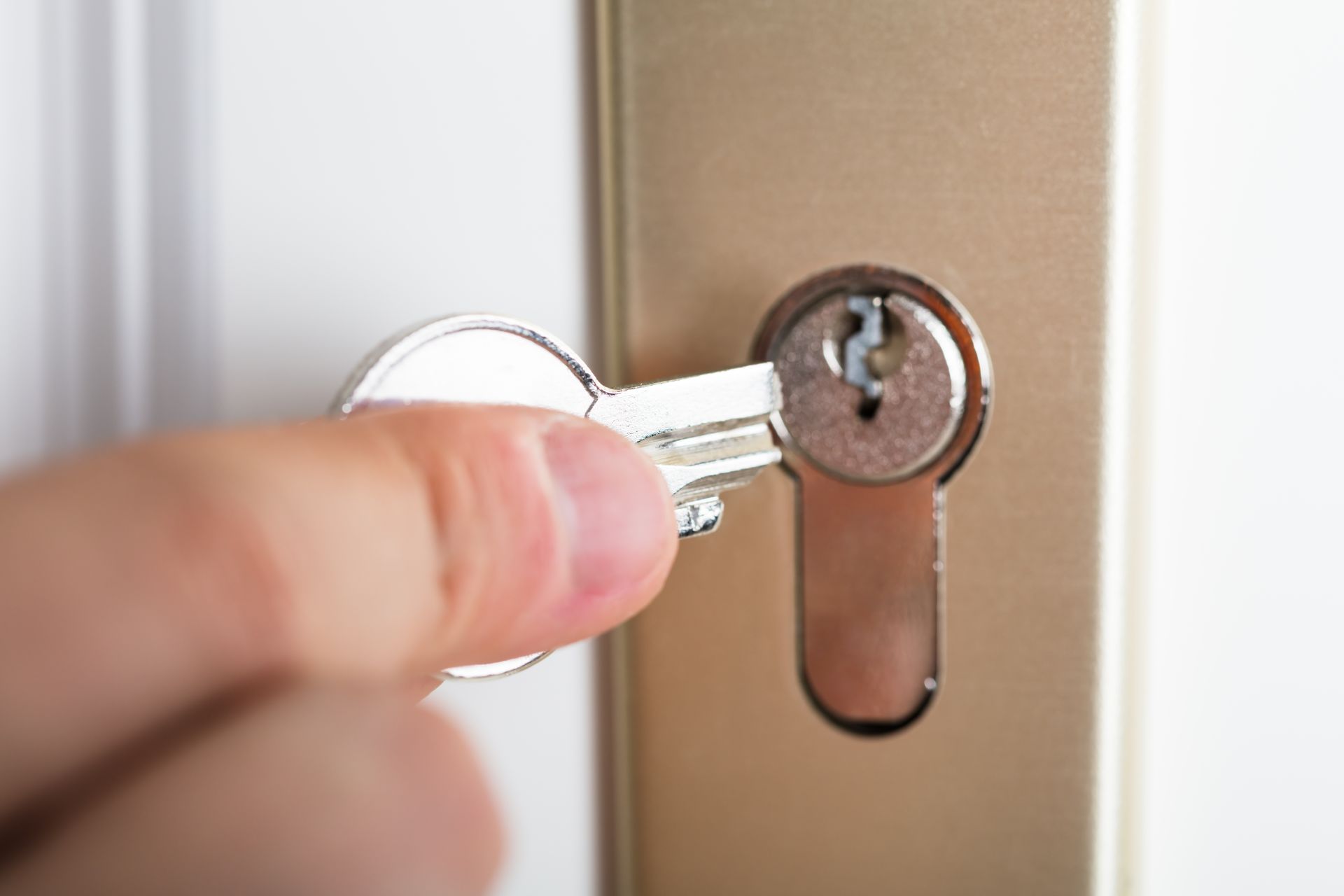 A person is holding a key in a door lock.