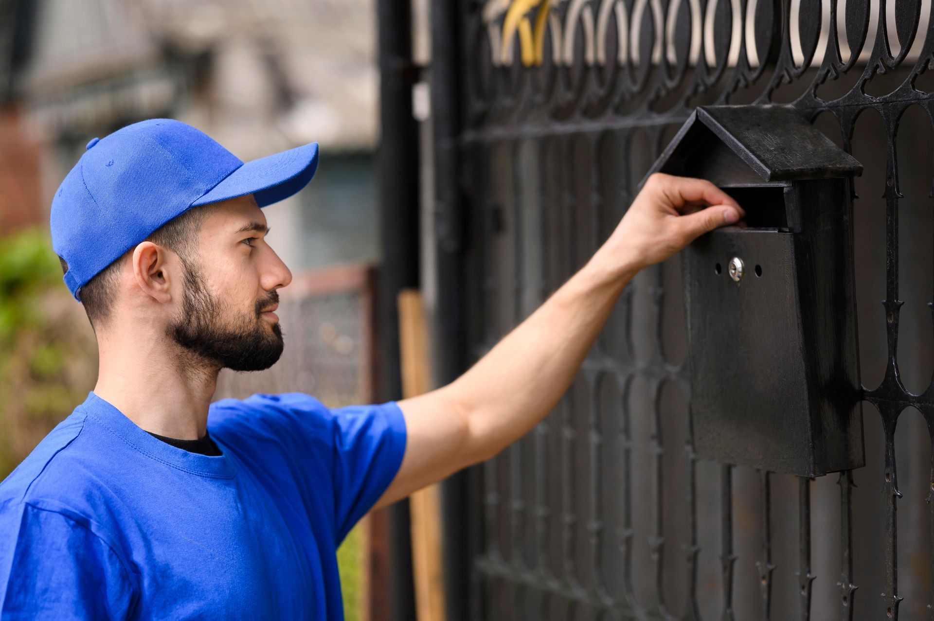 A delivery man is putting a letter in a mailbox.