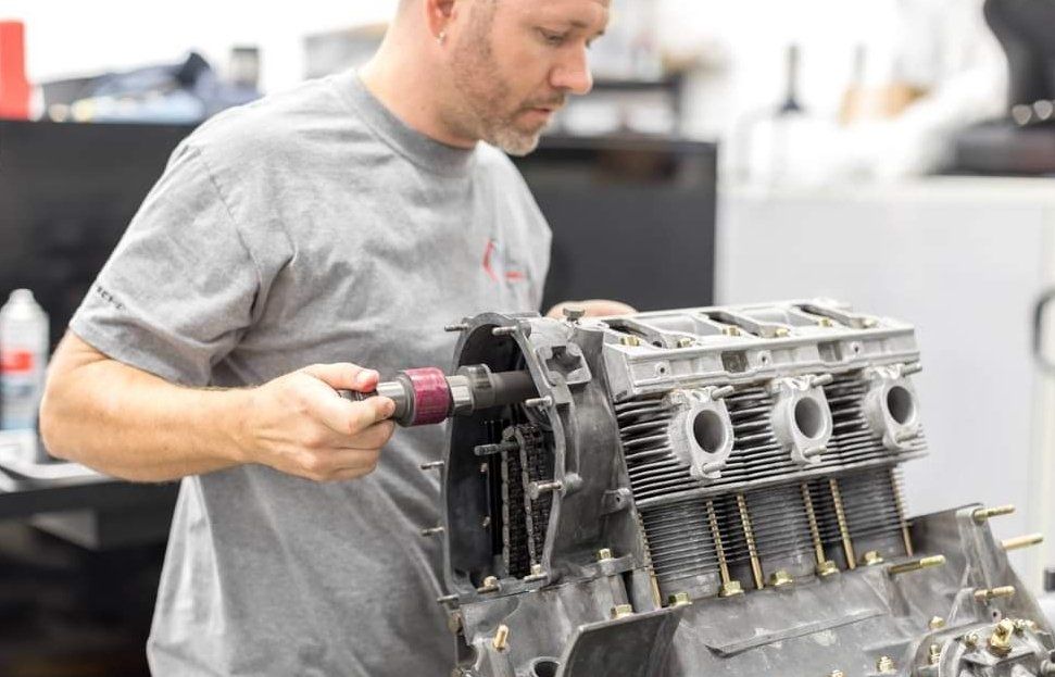 A man is working on a car engine in a garage.