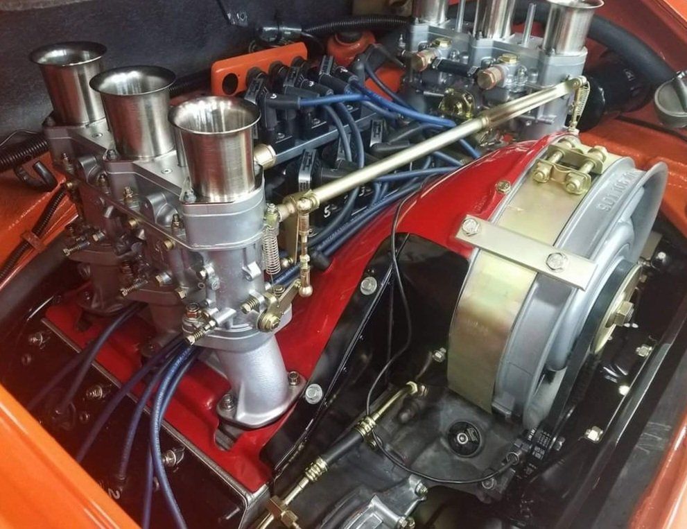 A close up of a car engine with many carburetors
