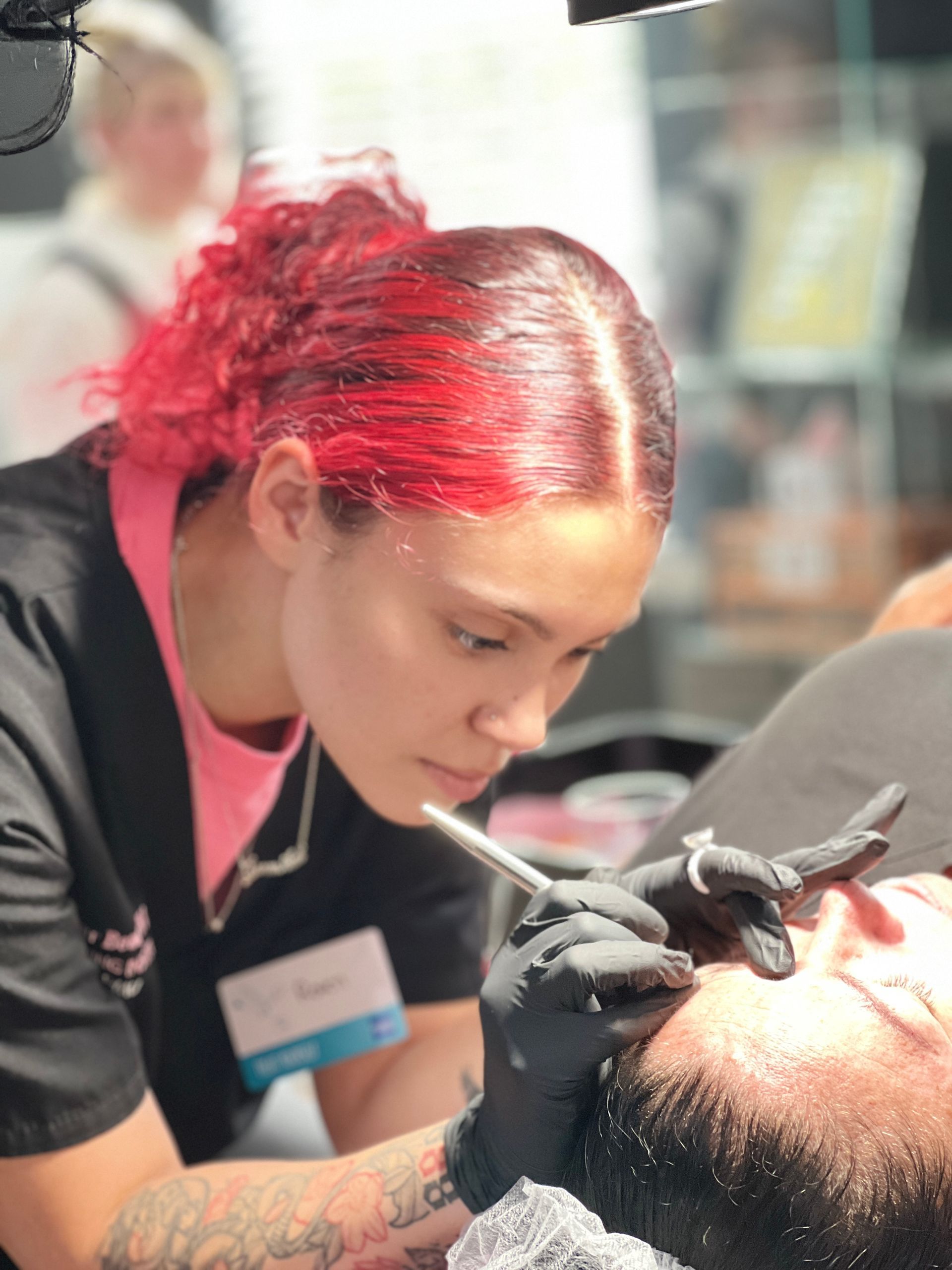 A woman with red hair is shaving a man 's beard.