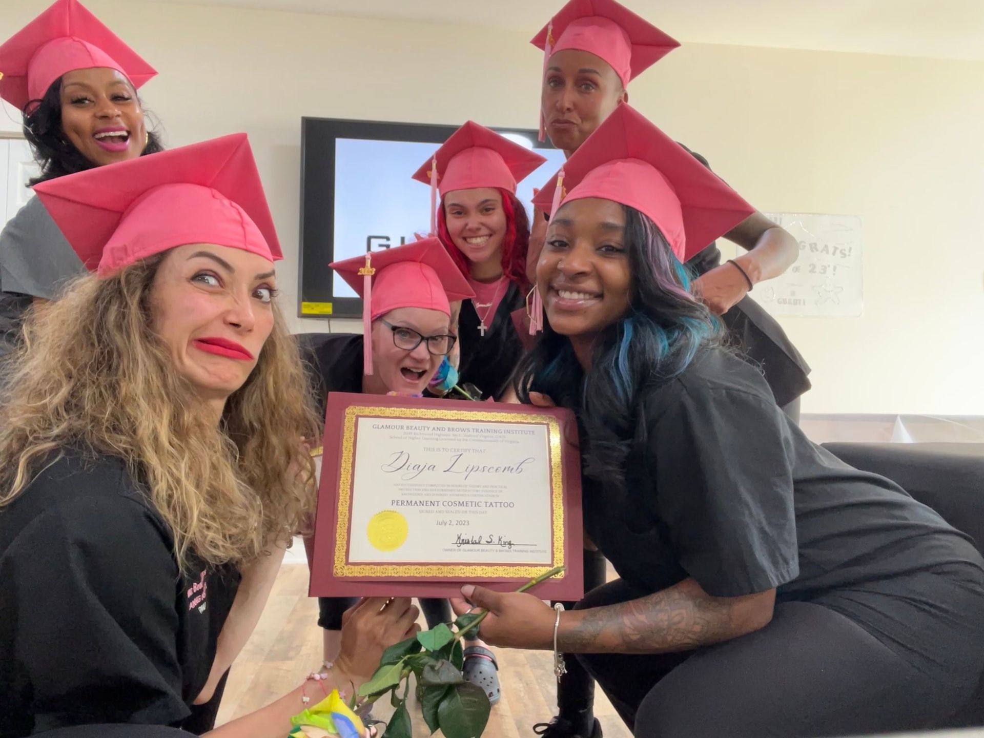 A group of women wearing graduation caps and gowns are holding a certificate.