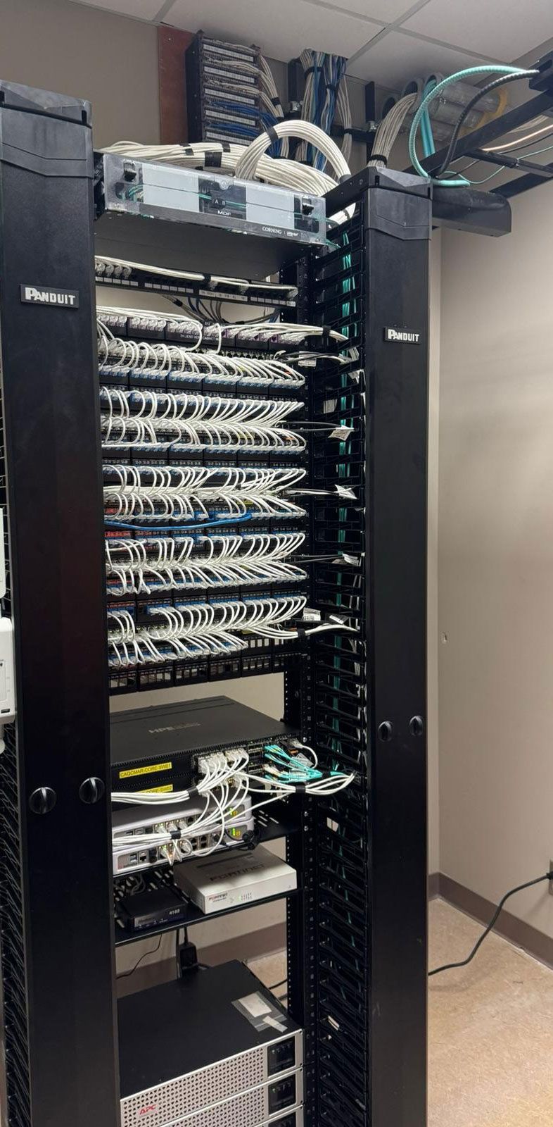 Server rack in a room with various network devices and cables.