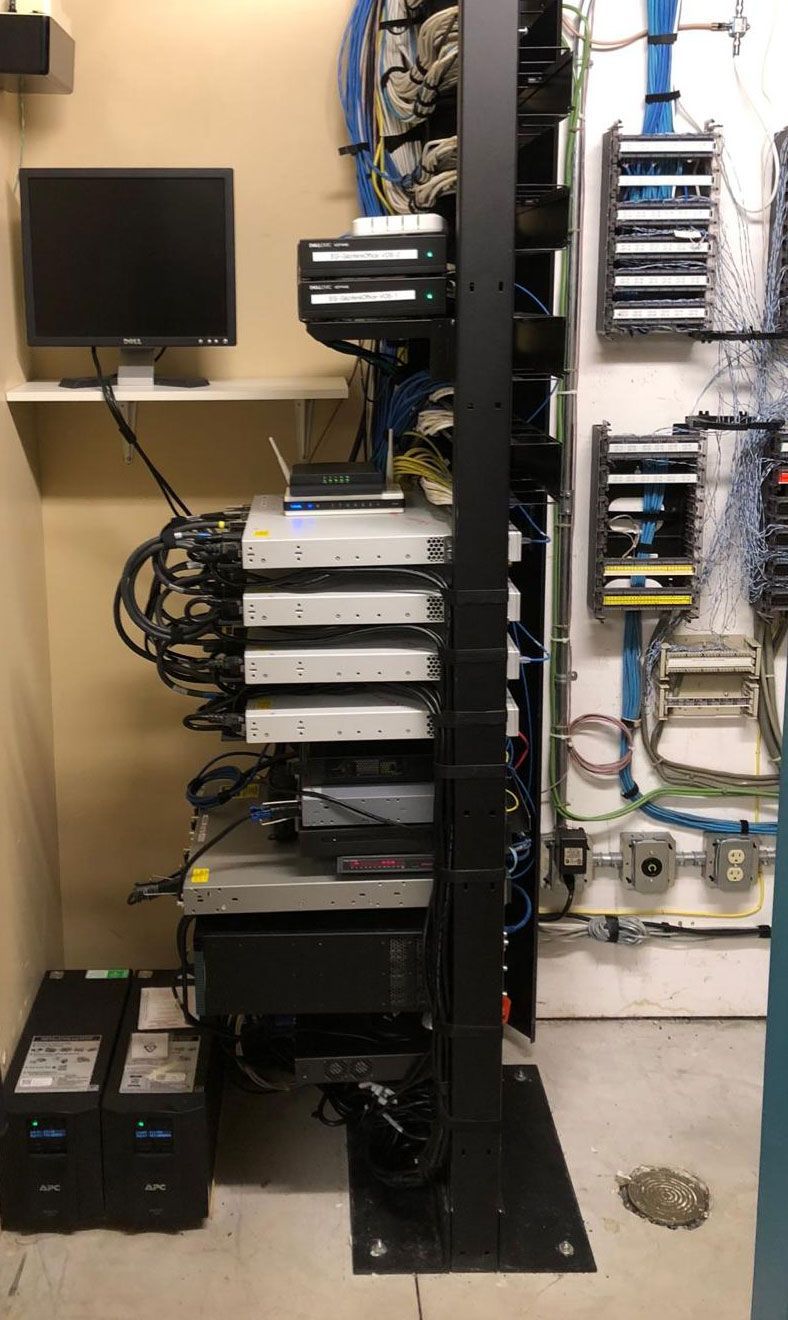 Server rack in a utility room with mounted servers, a monitor, and UPS units.