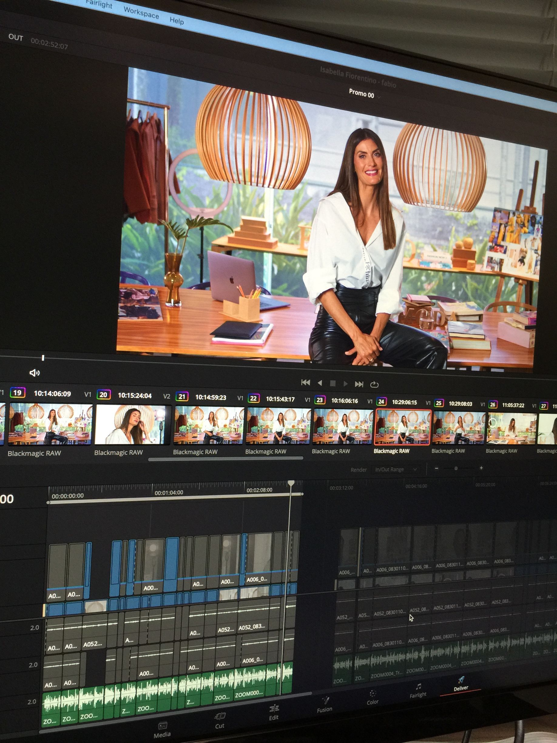 Mulher de camisa branca e calça de couro em uma tela de edição de vídeo. Cenário de estúdio, linha do tempo de edição e clipes visíveis.