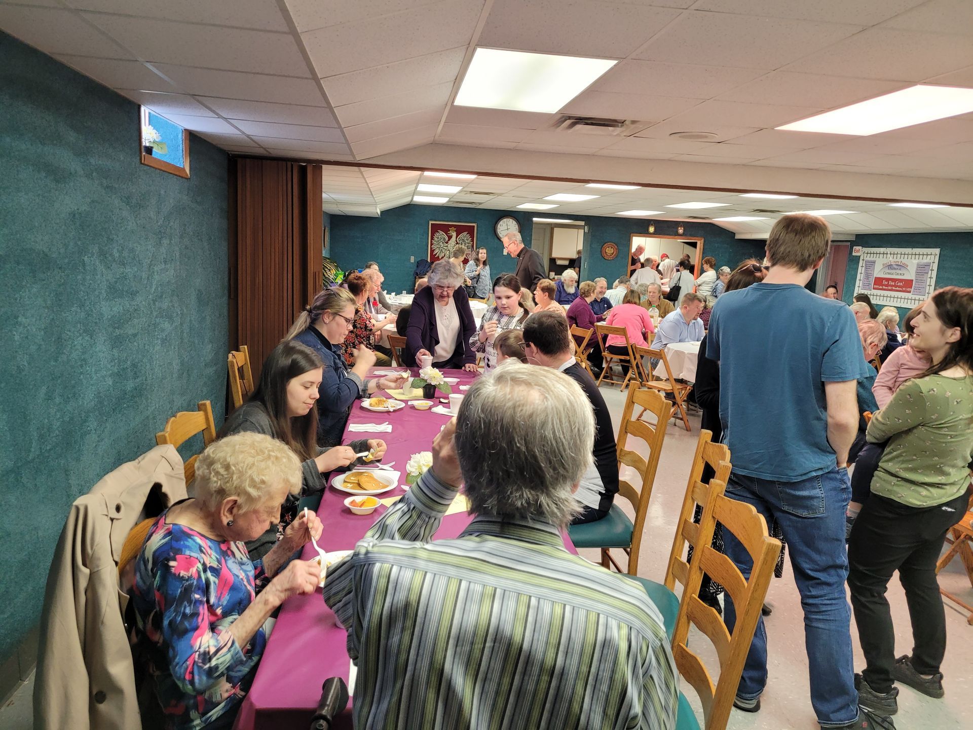 A group of people are sitting at tables in a room eating food.