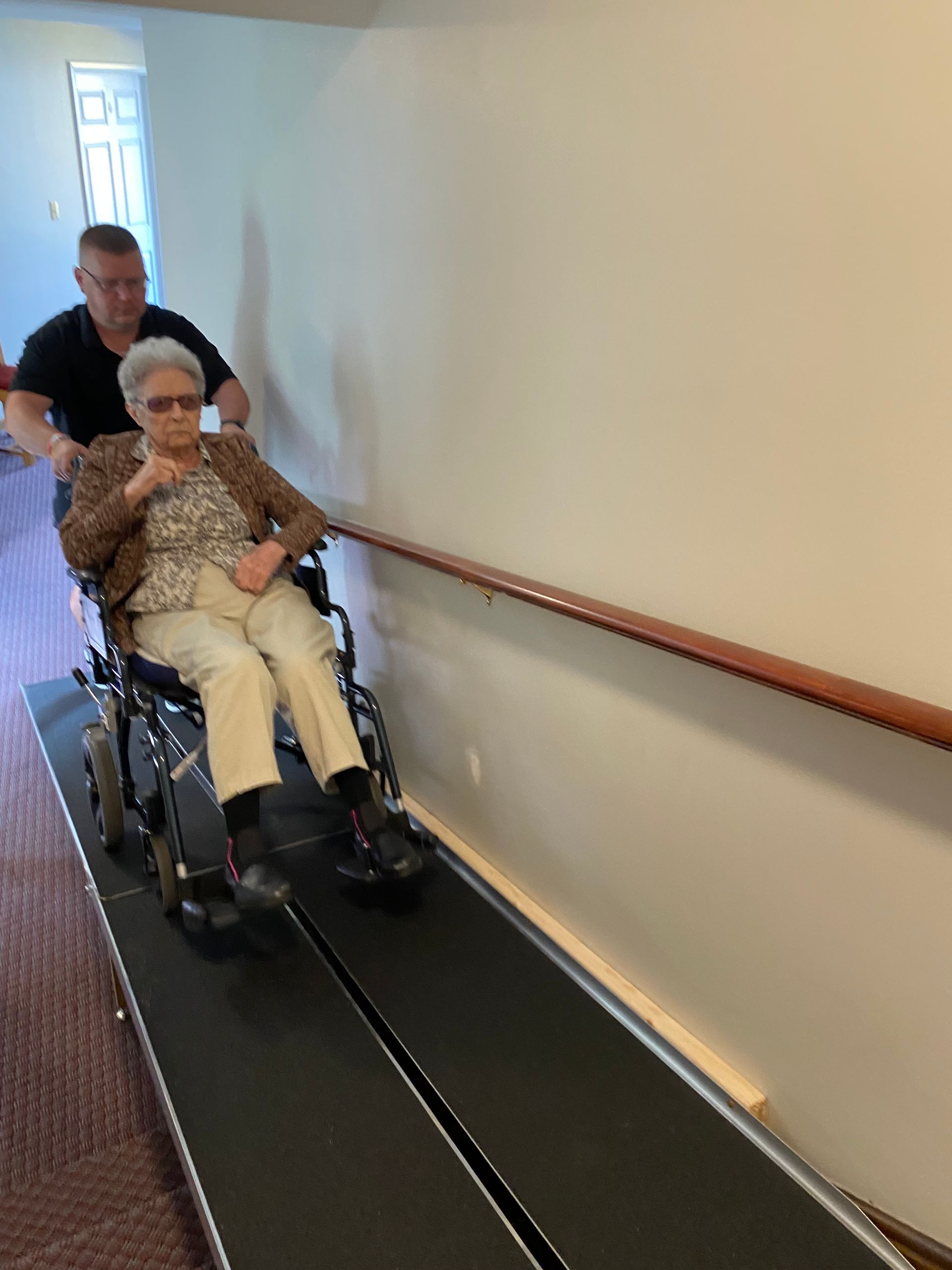 A woman in a wheelchair is being pushed down a ramp by a man