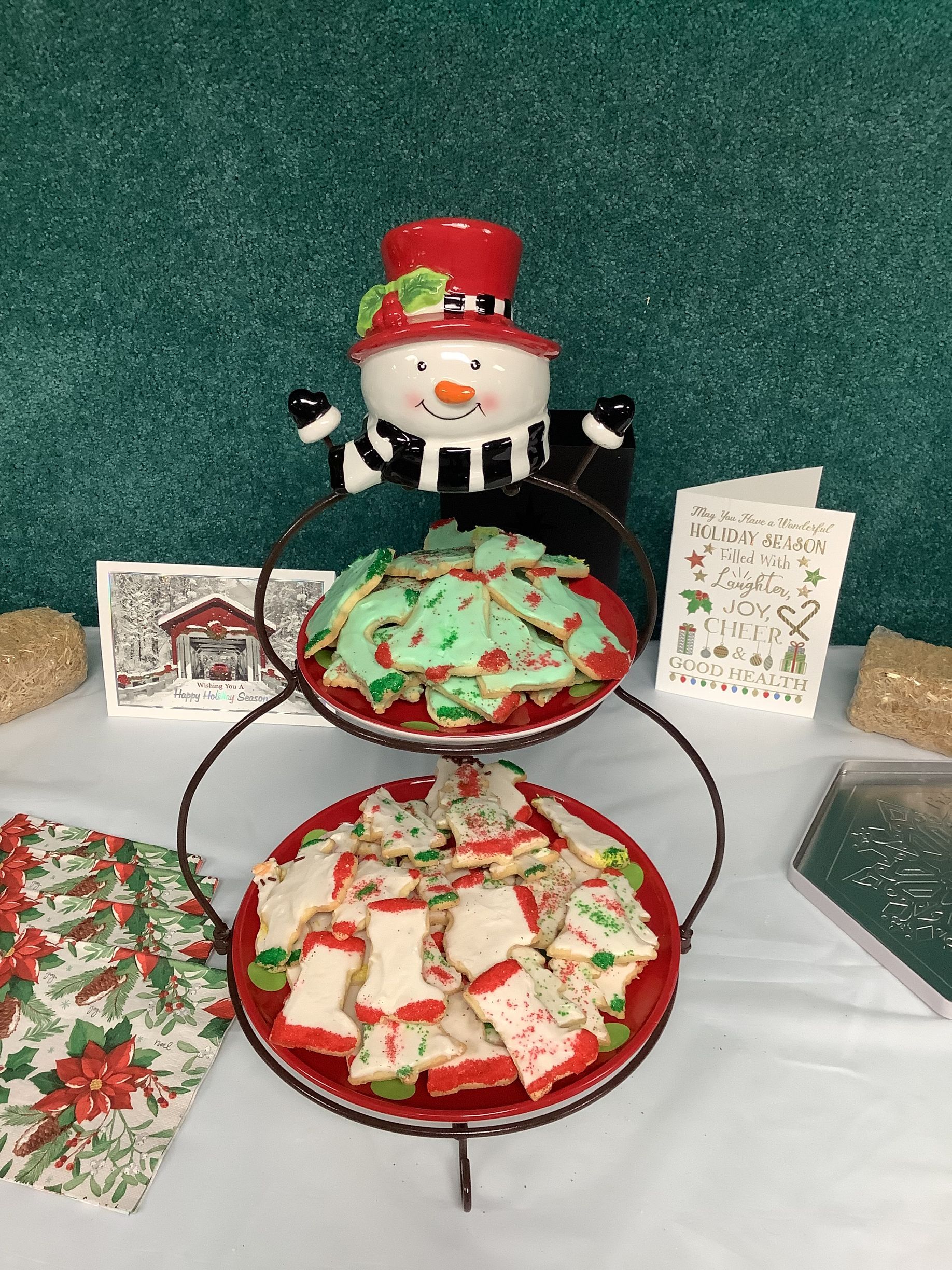 A table topped with plates of christmas cookies and a snowman figurine.