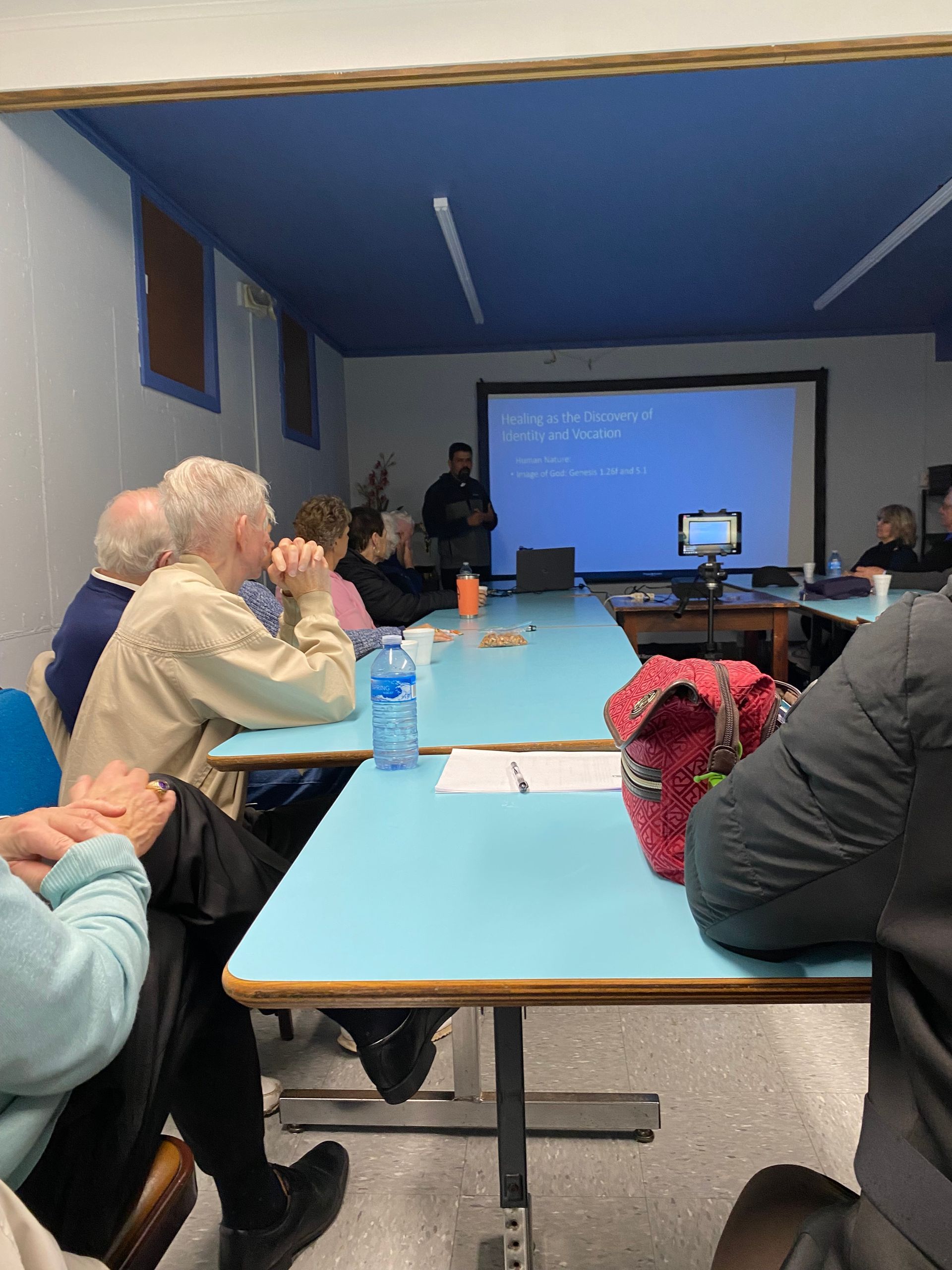 A group of people are sitting at tables watching a presentation