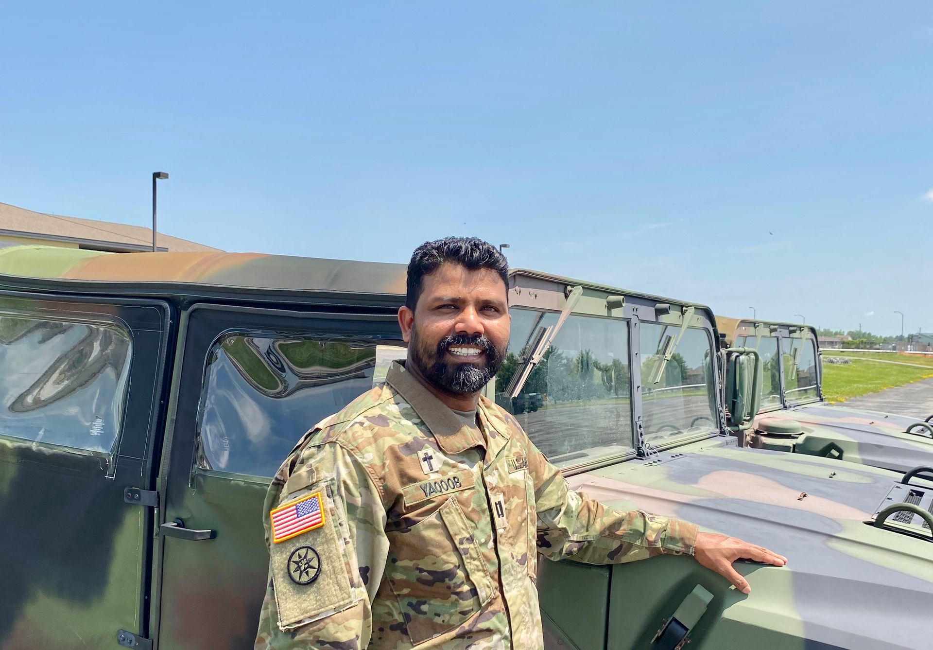A man in a military uniform is standing next to a military vehicle.