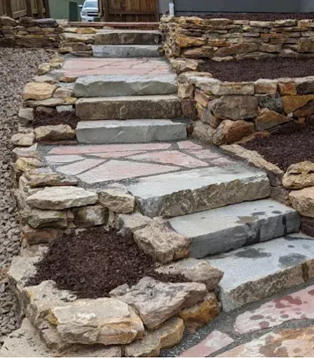 Stone steps with rock retaining walls, surrounded by mulch and gravel.