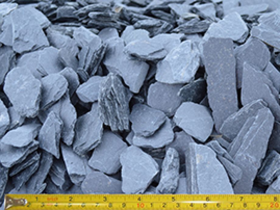 Pile of blue-gray slate chippings next to a yellow tape measure, suitable for landscaping.