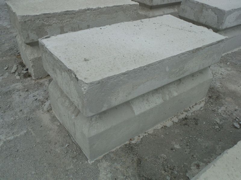 Two stacked gray concrete blocks, outside on a cement surface.