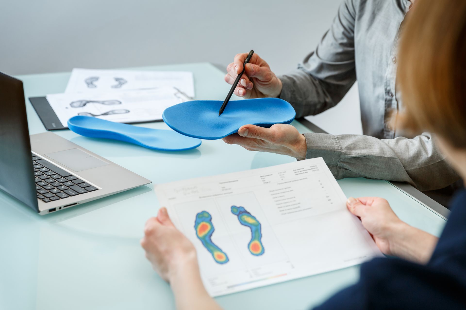 a woman is sitting at a table holding a pair of insoles .