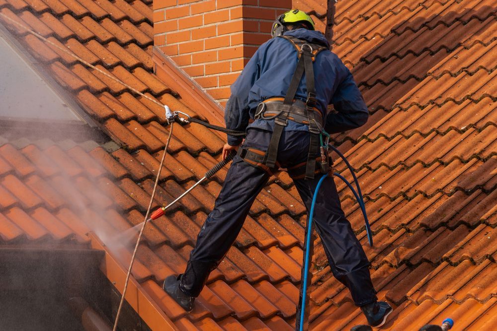 A Man is Cleaning a Roof With a High Pressure Washer — SOAKD Exterior Cleaning in Kariong, NSW