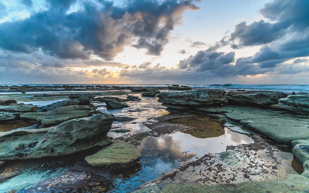 A Sunset Over a Rocky Beach With a Cloudy Sky — SOAKD Exterior Cleaning in Bateau Bay, NSW