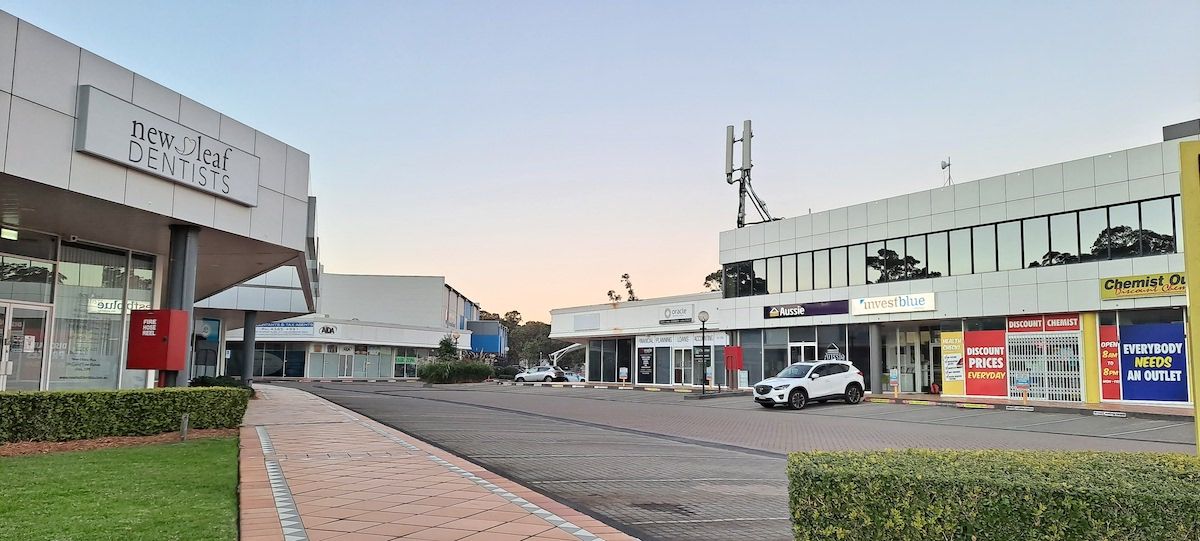 A White Car is Parked in Front of a Shopping Center — SOAKD Exterior Cleaning in Erina, NSW