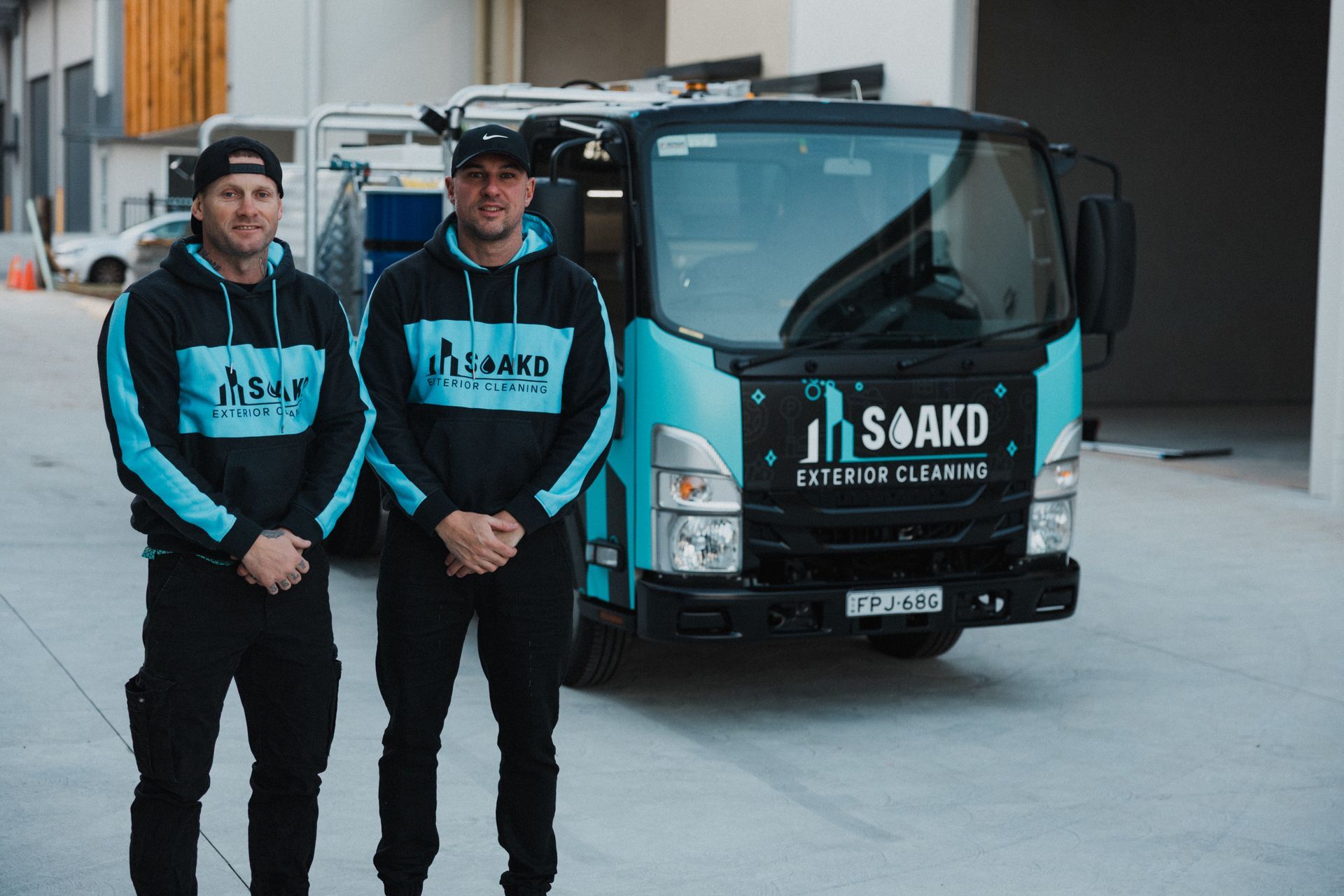 Person in Yellow Protective Suit Power-washes Sidewalk — SOAKD Exterior Cleaning in Central Coast, NSW