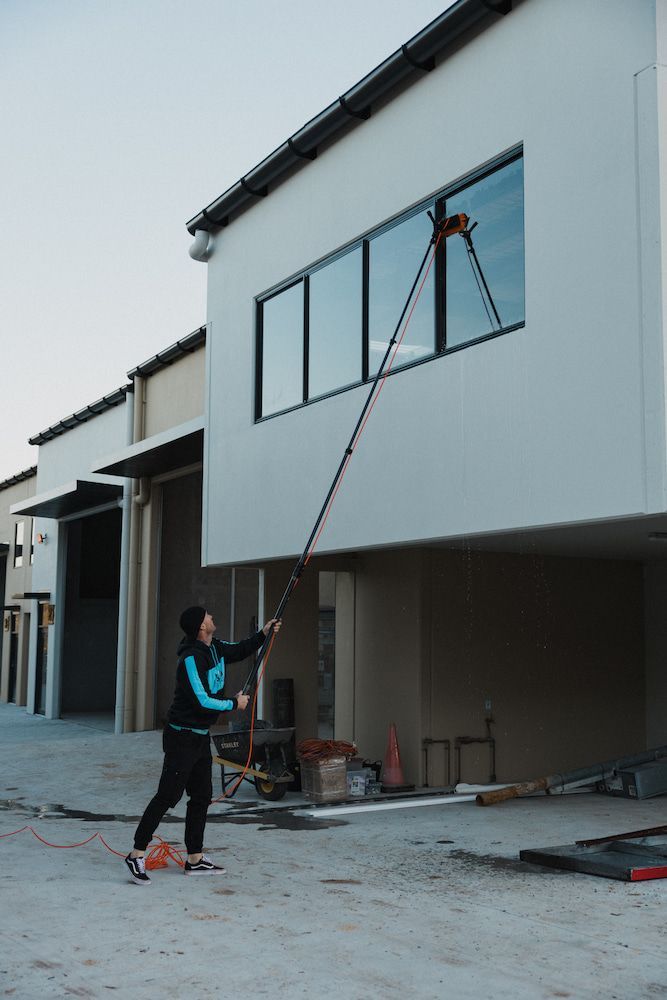 Person Washing Windows of a White Building With a Long Pole — SOAKD Exterior Cleaning in Terrigal, NSW