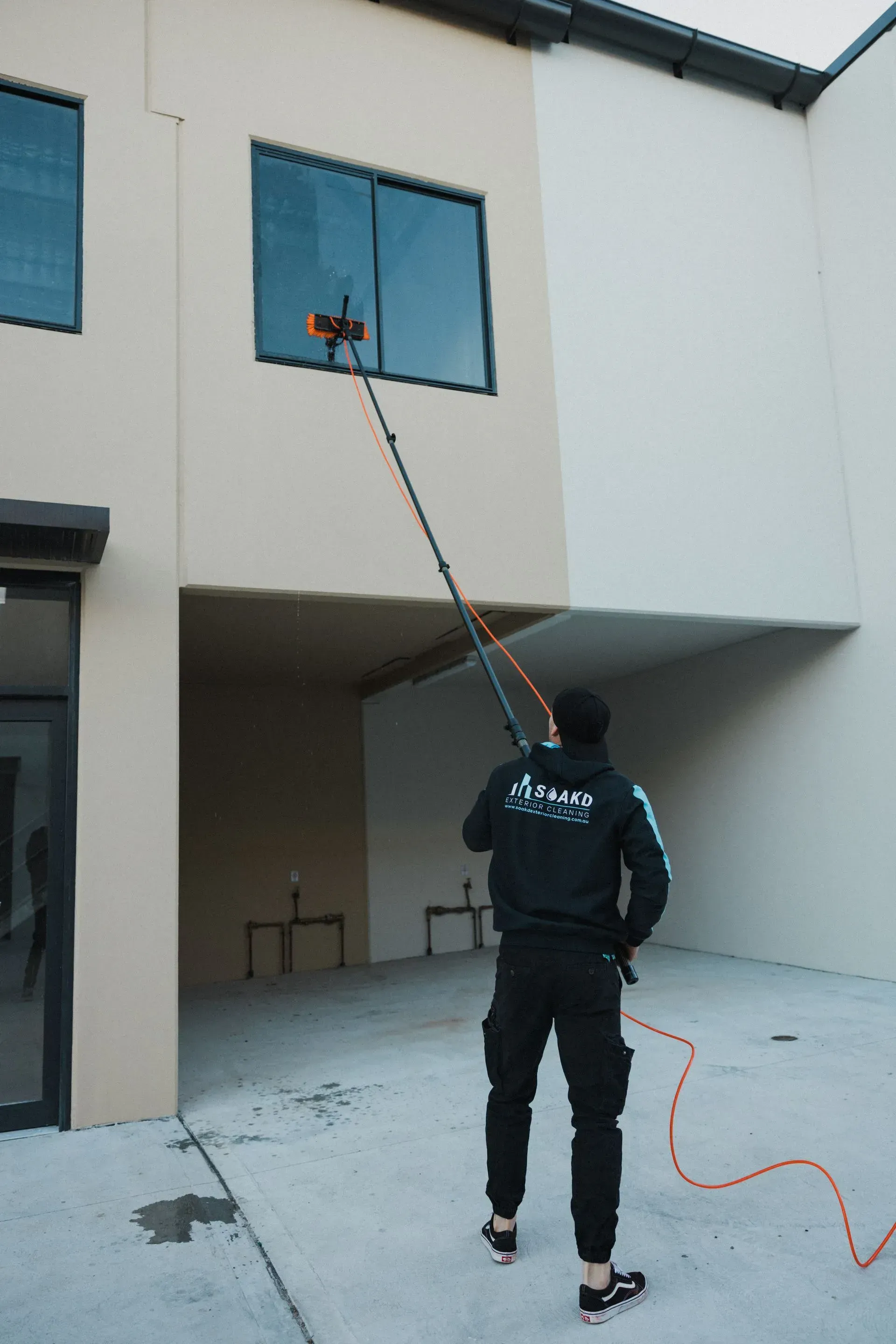 Man Washing a Window With a Long Pole — SOAKD Exterior Cleaning in Kariong, NSW