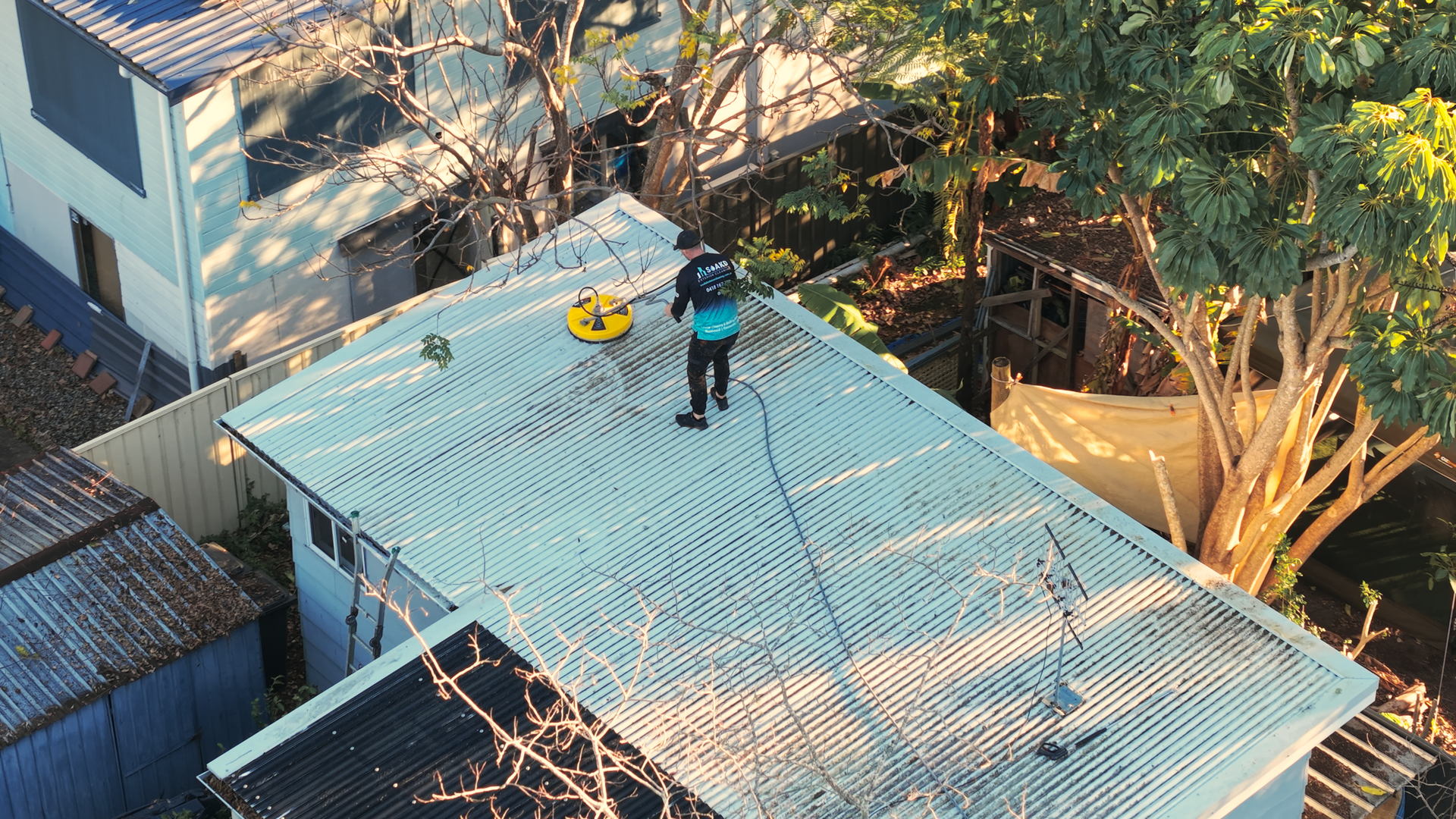 A Person is Cleaning the Roof of a House With a High Pressure Washer — SOAKD Exterior Cleaning in Central Coast, NSW