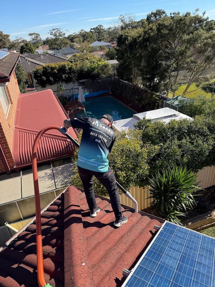 A Person is Cleaning a Gutter From Leaves on a Roof — SOAKD Exterior Cleaning in Kariong, NSW