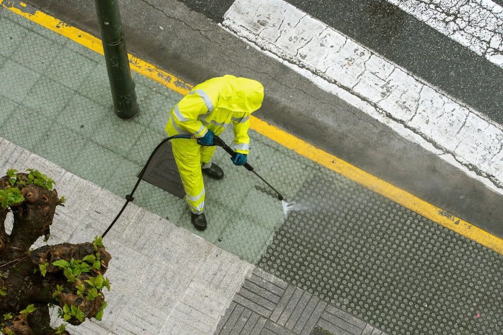 Person in Yellow Protective Suit Power-washes Sidewalk — SOAKD Exterior Cleaning in Kariong, NSW