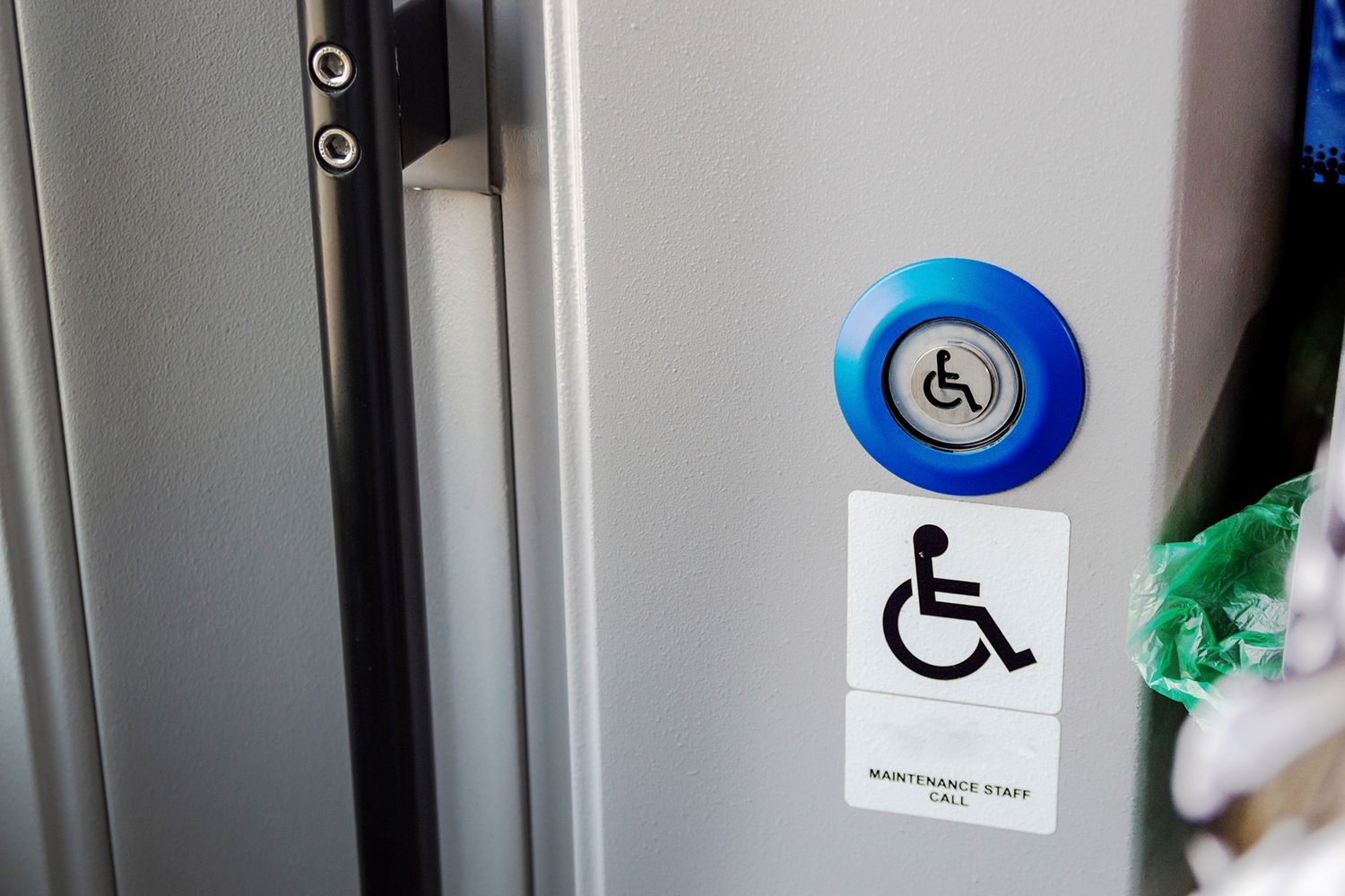 Blue button with wheelchair symbol on a bus door, next to a wheelchair access sticker. Blue button with wheelchair symbol on a bus door, next to a wheelchair access sticker.