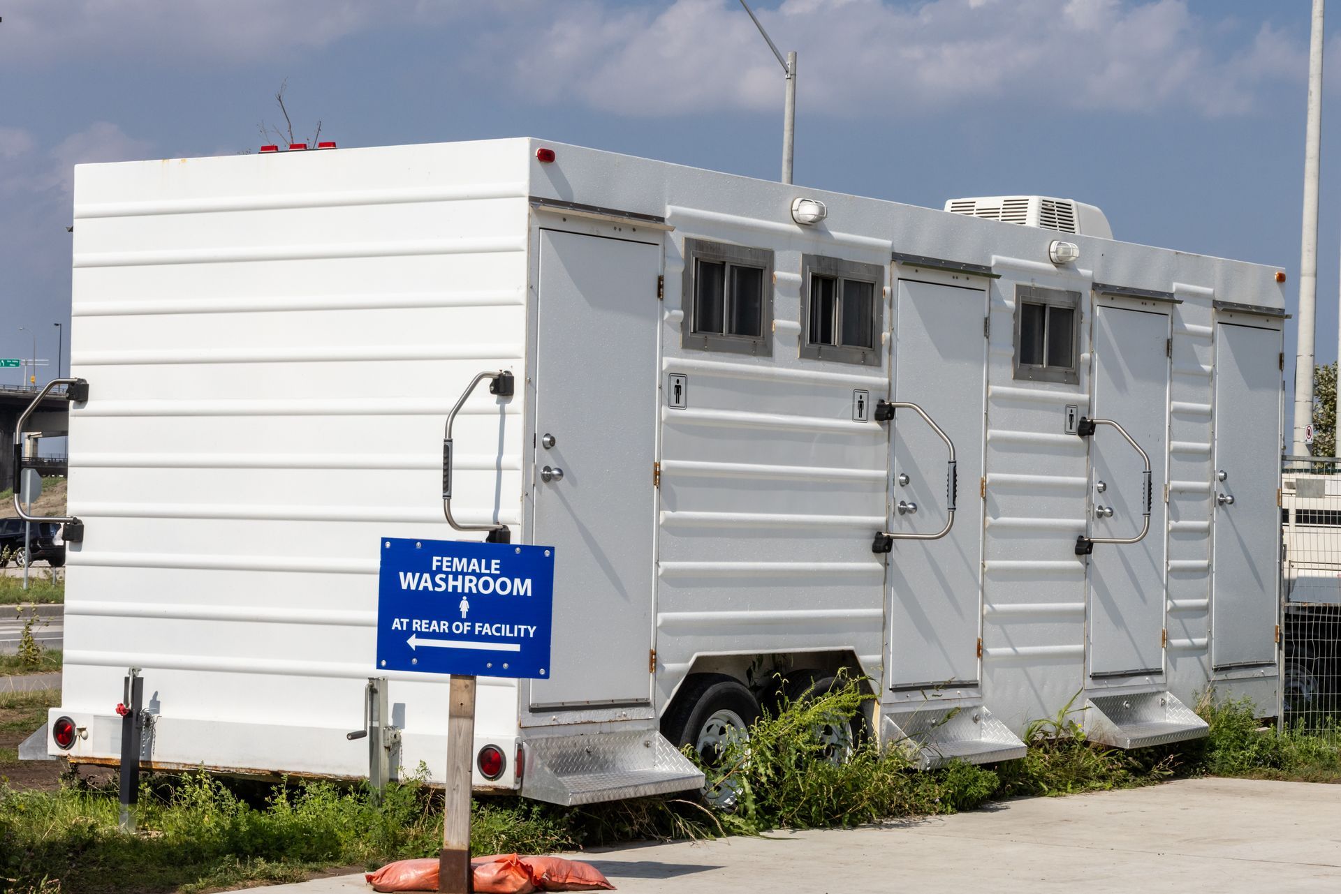 A luxury portable white restroom trailer with multiple doors parked on site