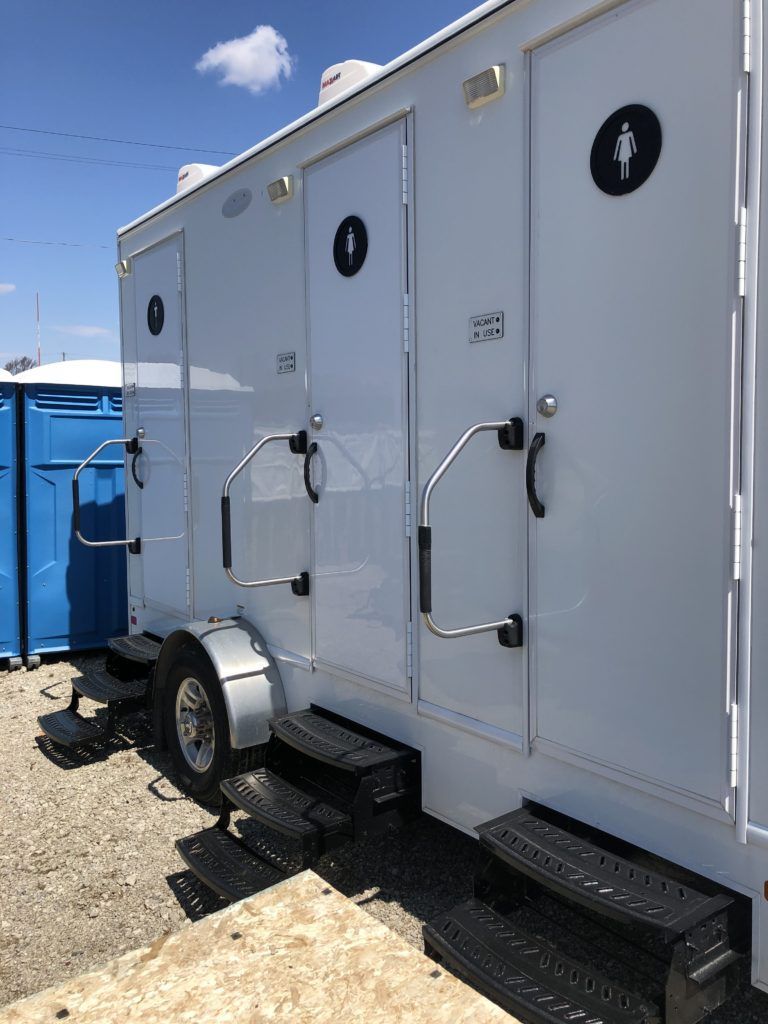 Portable white restroom trailer with three individual stalls and steps. Portable white restroom trailer with three individual stalls and steps.