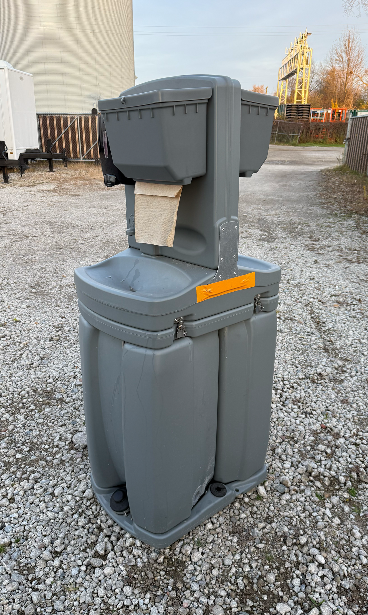 Interior view of a portable restroom with a toilet, trash can, and sink.