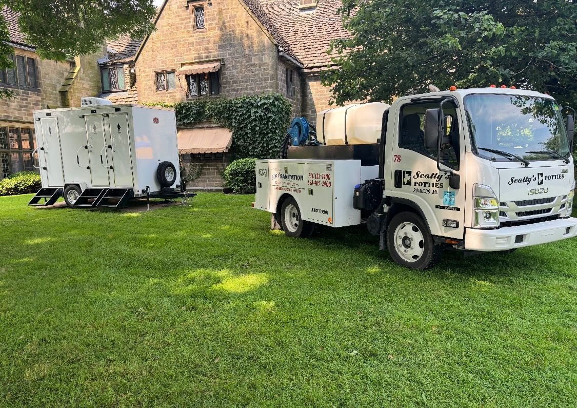 White utility truck and trailer on green lawn in front of a stone building. White utility truck and trailer on green lawn in front of a stone building.