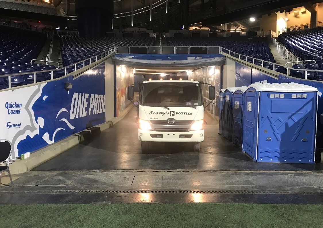Row of blue portable toilets lining a sidewalk, likely for a public event. Row of blue portable toilets lining a sidewalk, likely for a public event.