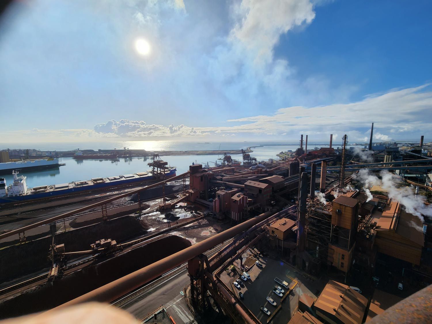 an aerial view of a factory with a large body of water in the background