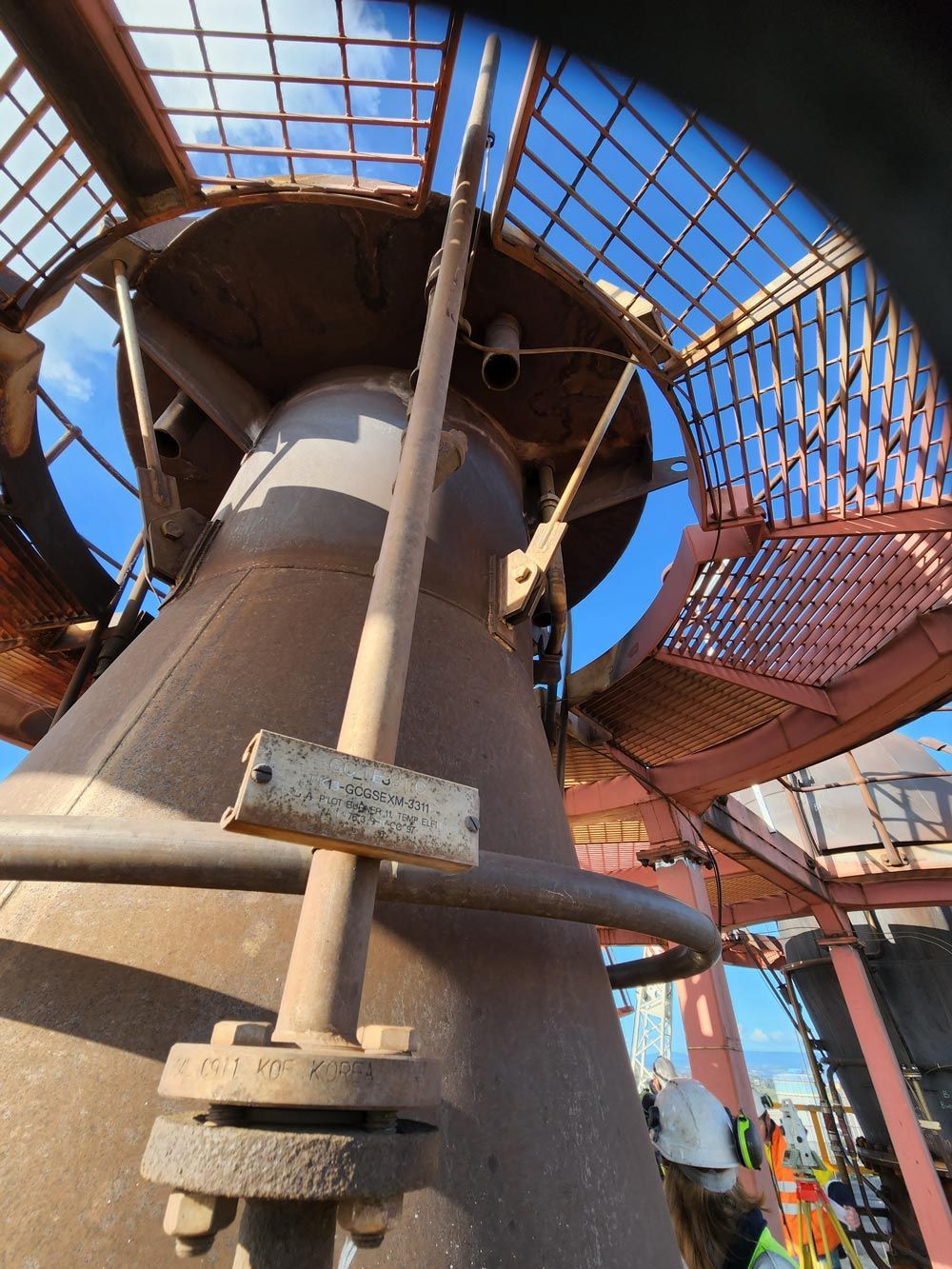 a large metal structure with stairs and a blue sky in the background