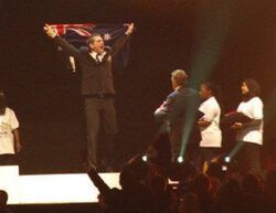 a man is standing on a stage holding an australian flag