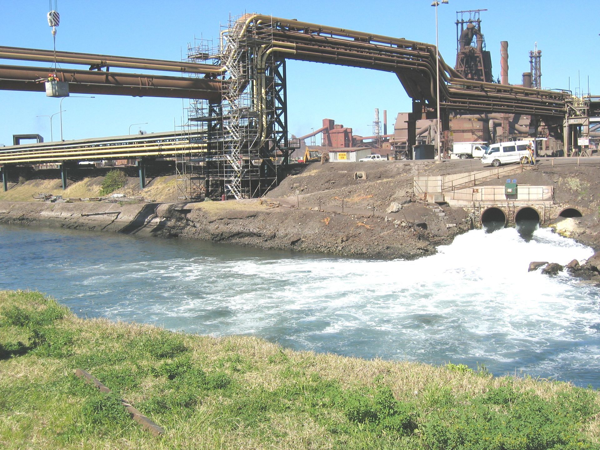 a large body of water with a factory in the background