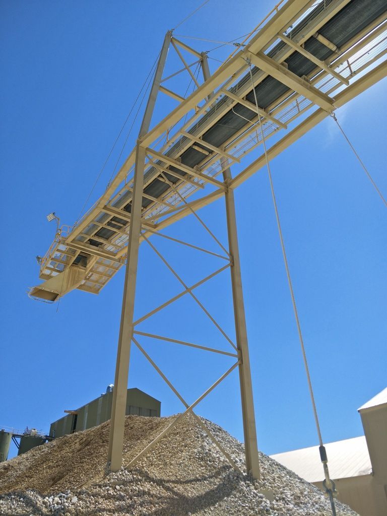 a conveyor belt over a pile of gravel
