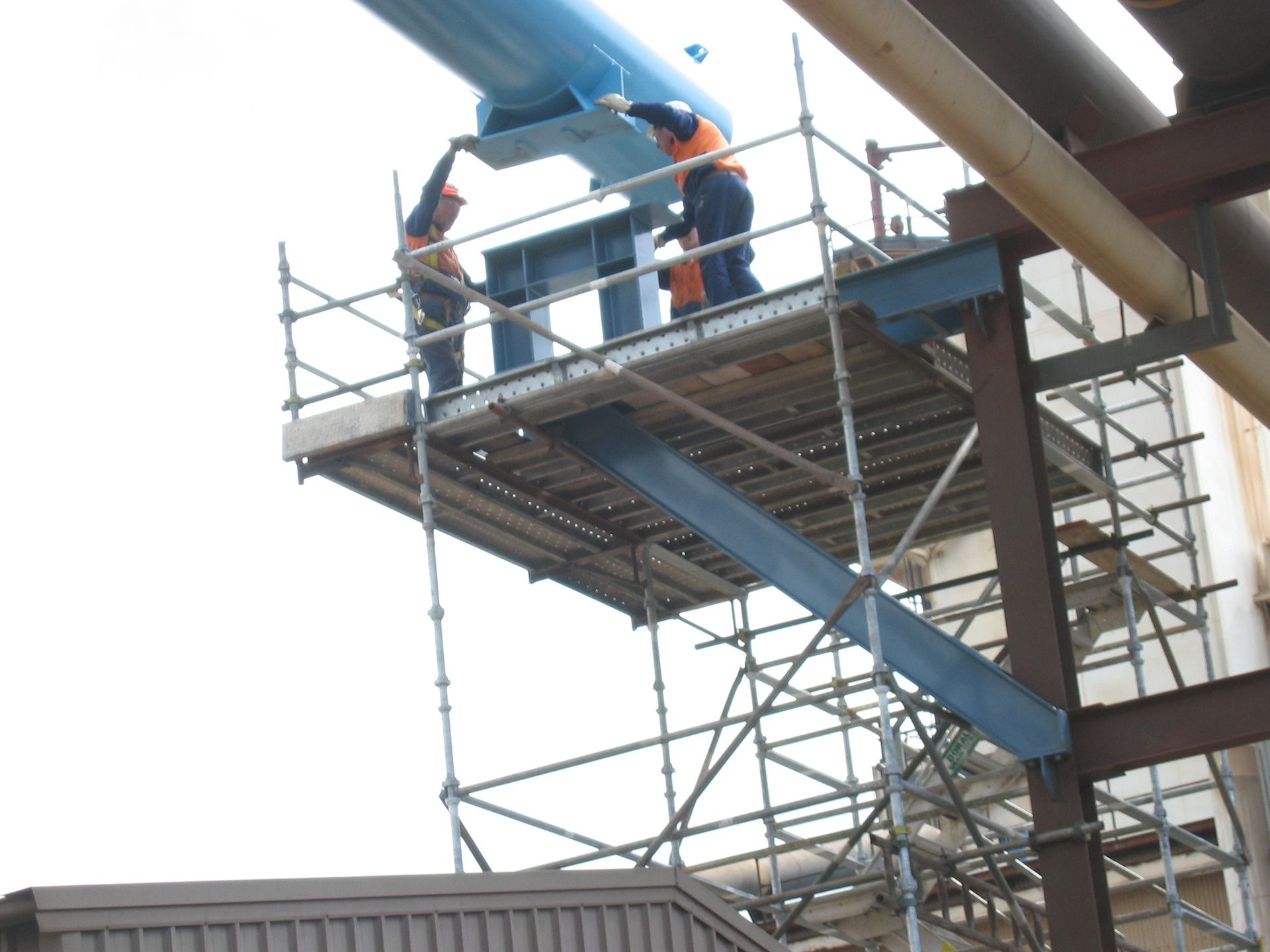 two men are standing on a scaffolding on top of a building