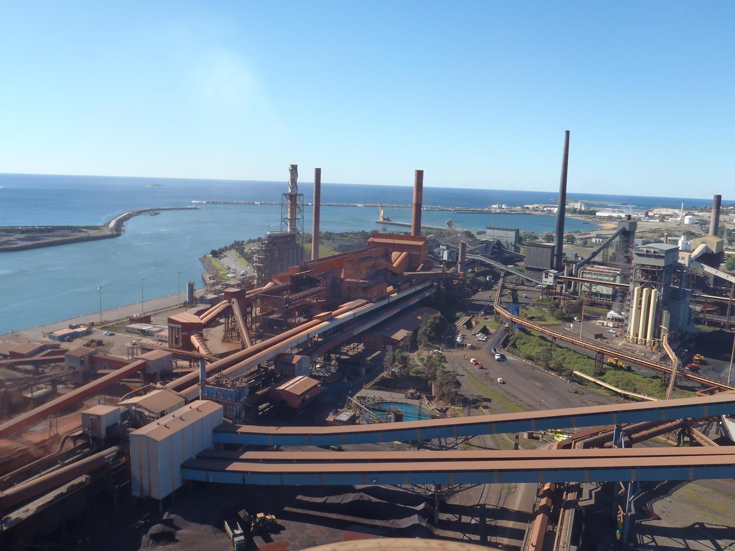 an aerial view of a factory with a large body of water in the background