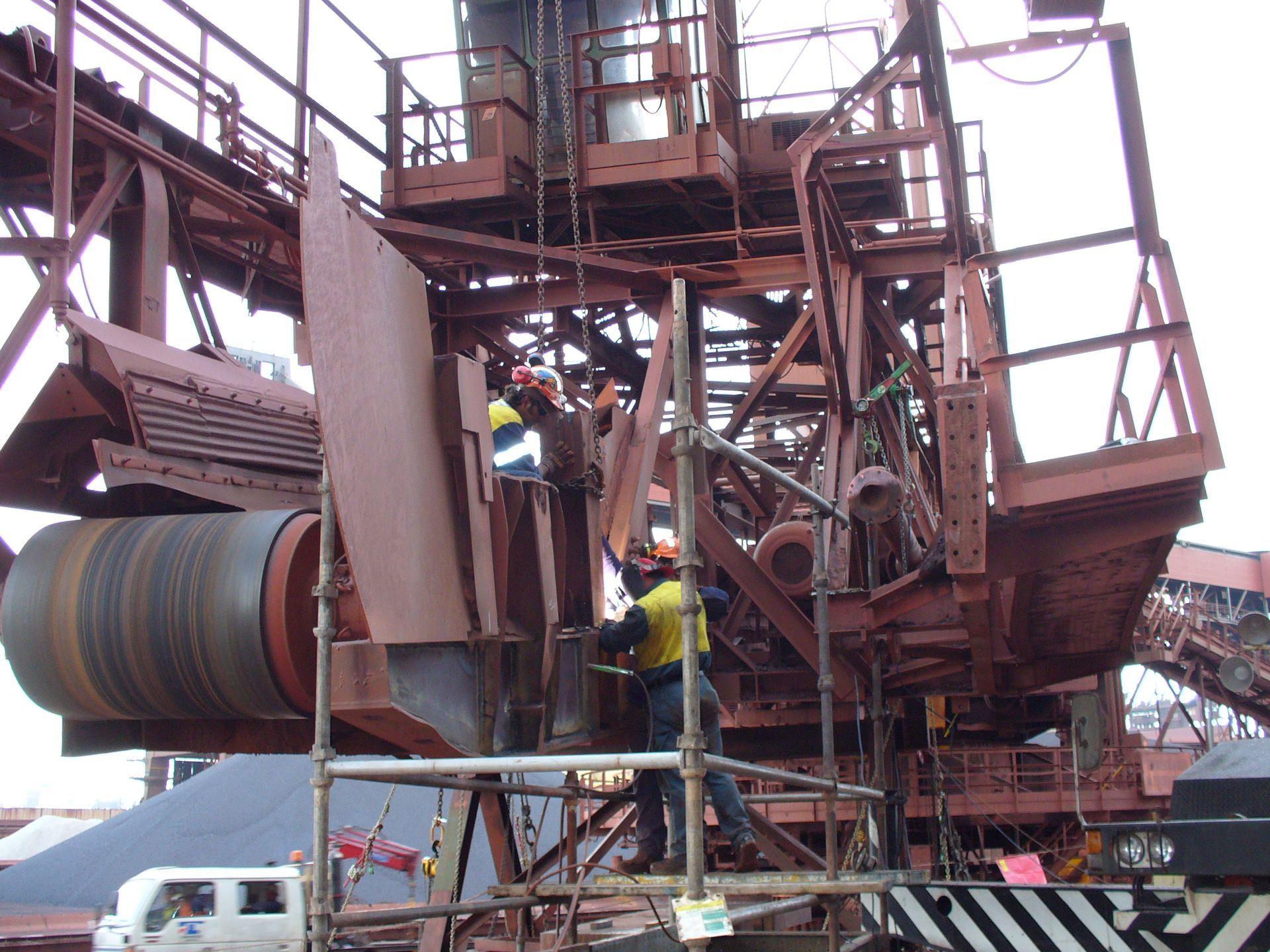 a man in a yellow shirt is working on a large metal structure