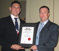 two men in suits and ties are holding a framed certificate
