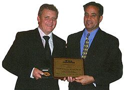 two men in suits and ties are holding a plaque