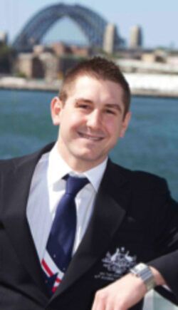 a man in a suit and tie is smiling with a bridge in the background