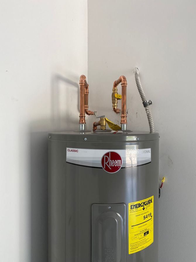 A gray water heater is sitting in a corner of a room.