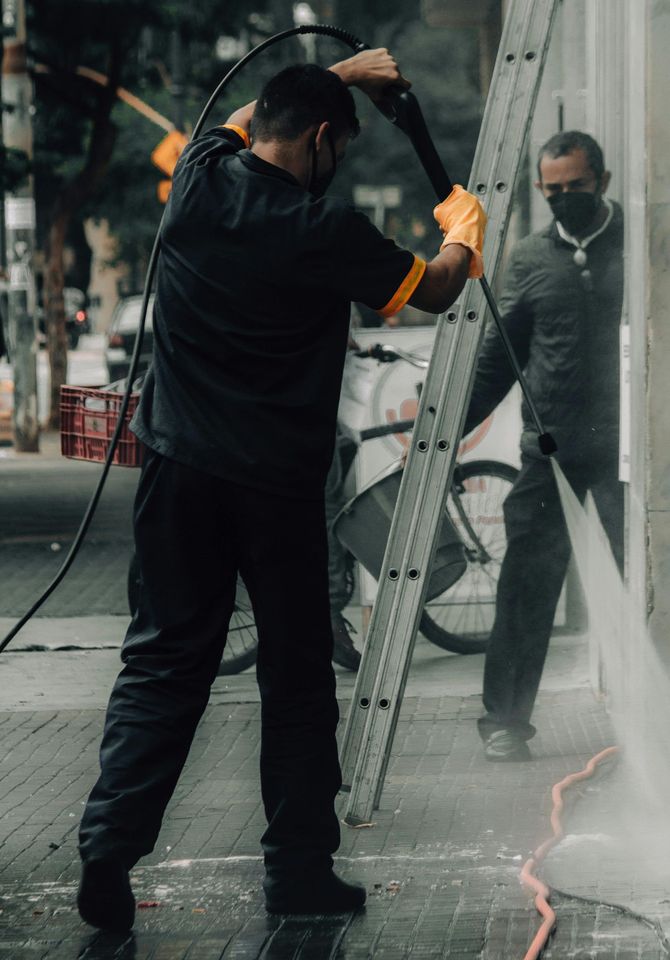 A man is cleaning a window with a high pressure washer.