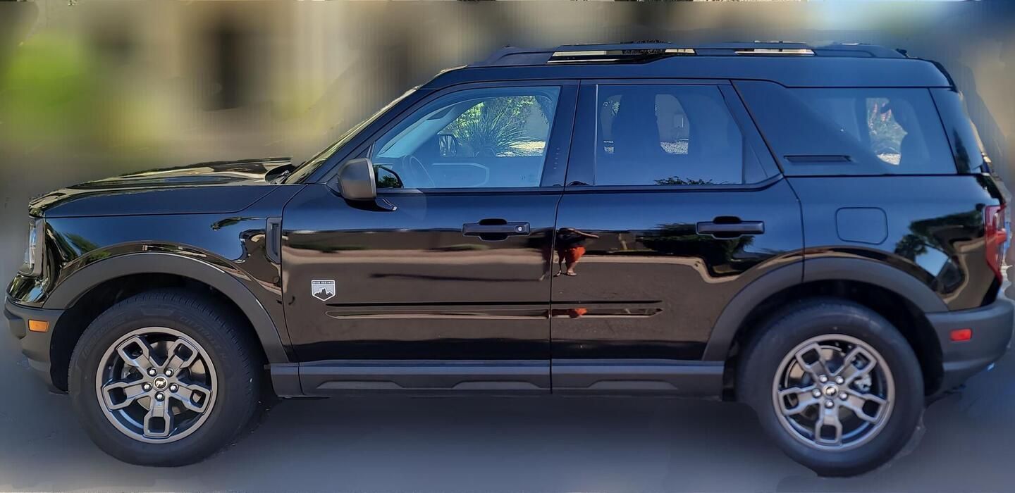 A black ford bronco sport is parked on the side of the road.
