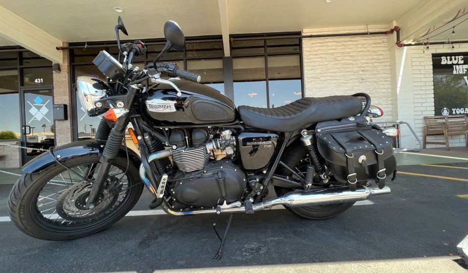 A black motorcycle is parked in a parking lot in front of a building.