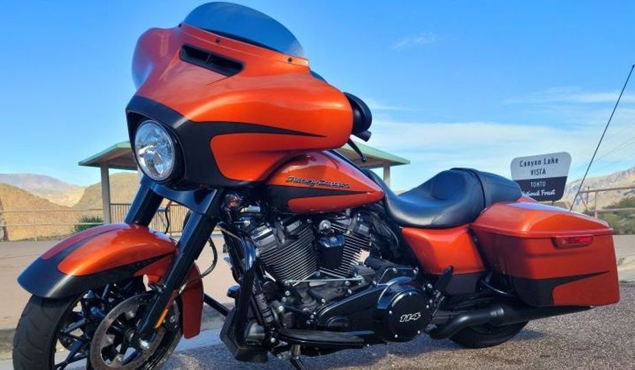 A red harley davidson motorcycle is parked on the side of the road.
