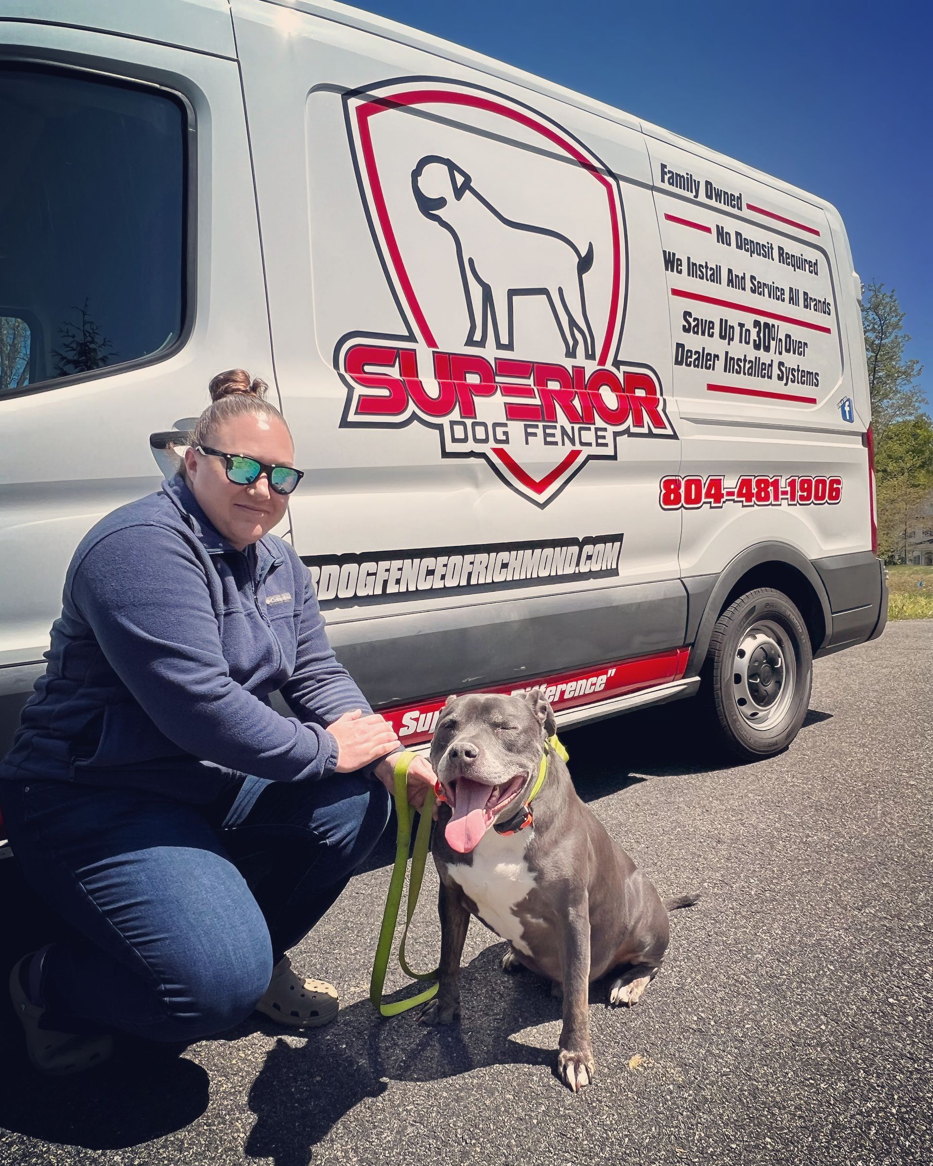 Woman kneels beside a dog in front of a van with a dog-themed logo.